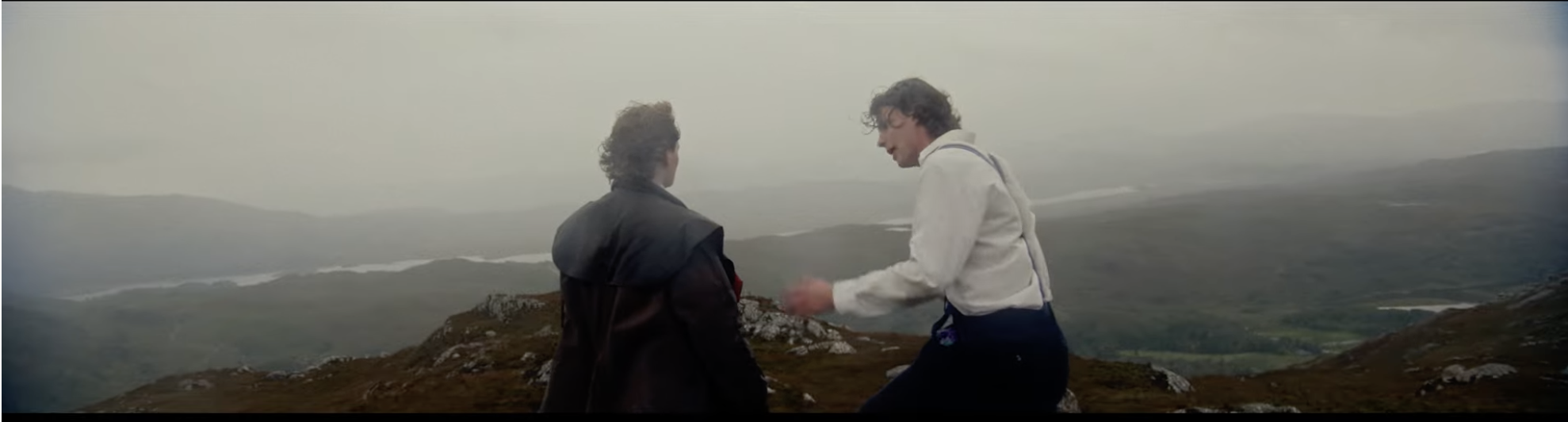 Film still — two figures on a misty Highland summit